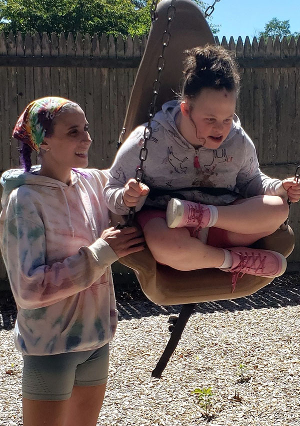 A girl swing in the park with a caretaker